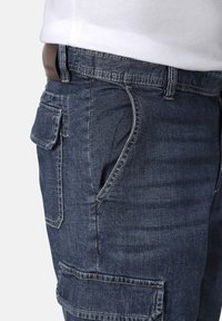 Denim cargo shorts in dark blue with a smooth texture, featuring front pockets, a side pocket, and stitching accents.