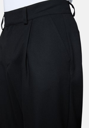 Black tailored trousers with side pockets, belt loops, and front pleats, worn with a white tucked-in top.