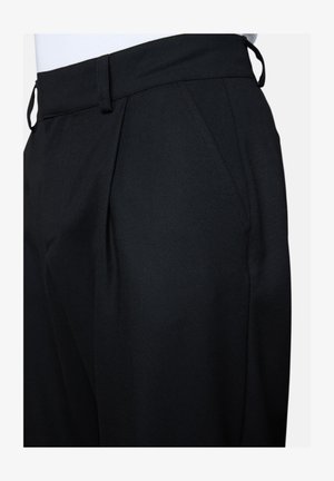 Schwarze maßgeschneiderte Hose mit Seitentaschen, Gürtelschlaufen und vorderen Falten, getragen mit einem weißen, hineingesteckten Top.