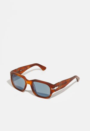 Gafas de sol de carey marrón con montura cuadrada gruesa y lentes azul oscuro. Los acentos plateados en las patillas realzan el diseño moderno.