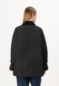 Black quilted jacket with a diamond pattern, long sleeves, and a velvet collar. Features a loose fit and a plain texture.