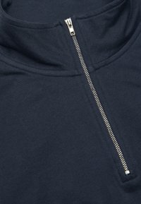 Marinblå, lätt pullover med hög krage och silvrig dragkedja, med slät, enfärgad tyg och rena söm detaljer.