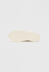 Soletta delle scarpe in crema con una superficie liscia e strutturata. Presenta motivi orizzontali e circolari per una migliore presa. Punta arrotondata e design flessibile.