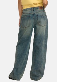 Denim bredde ben jeans i lys blå med en falmet finish, med høy midje, to baklommer og synlige sømdetaljer.