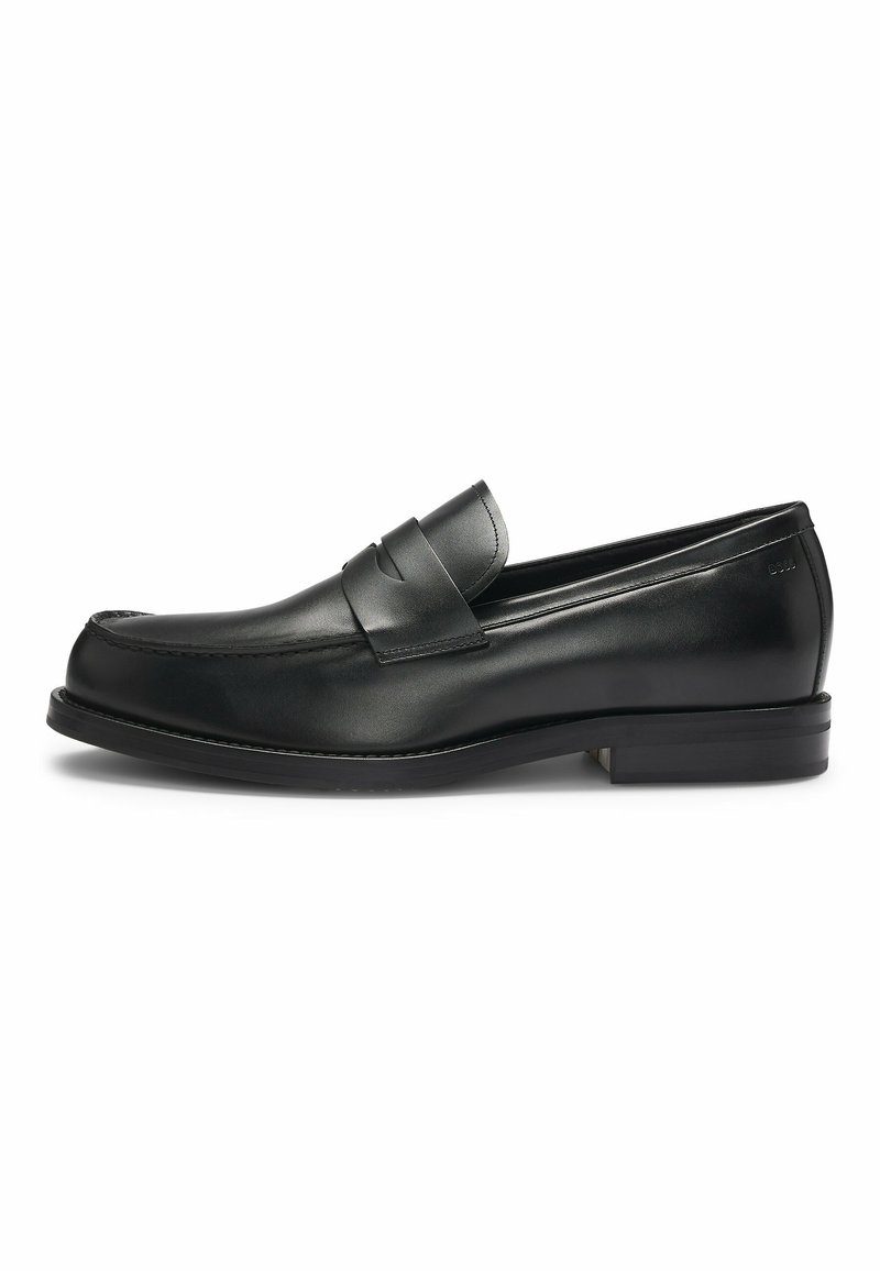 Black leather loafers with a rounded toe and stitched detailing, featuring a decorative strap across the upper and a low heel.
