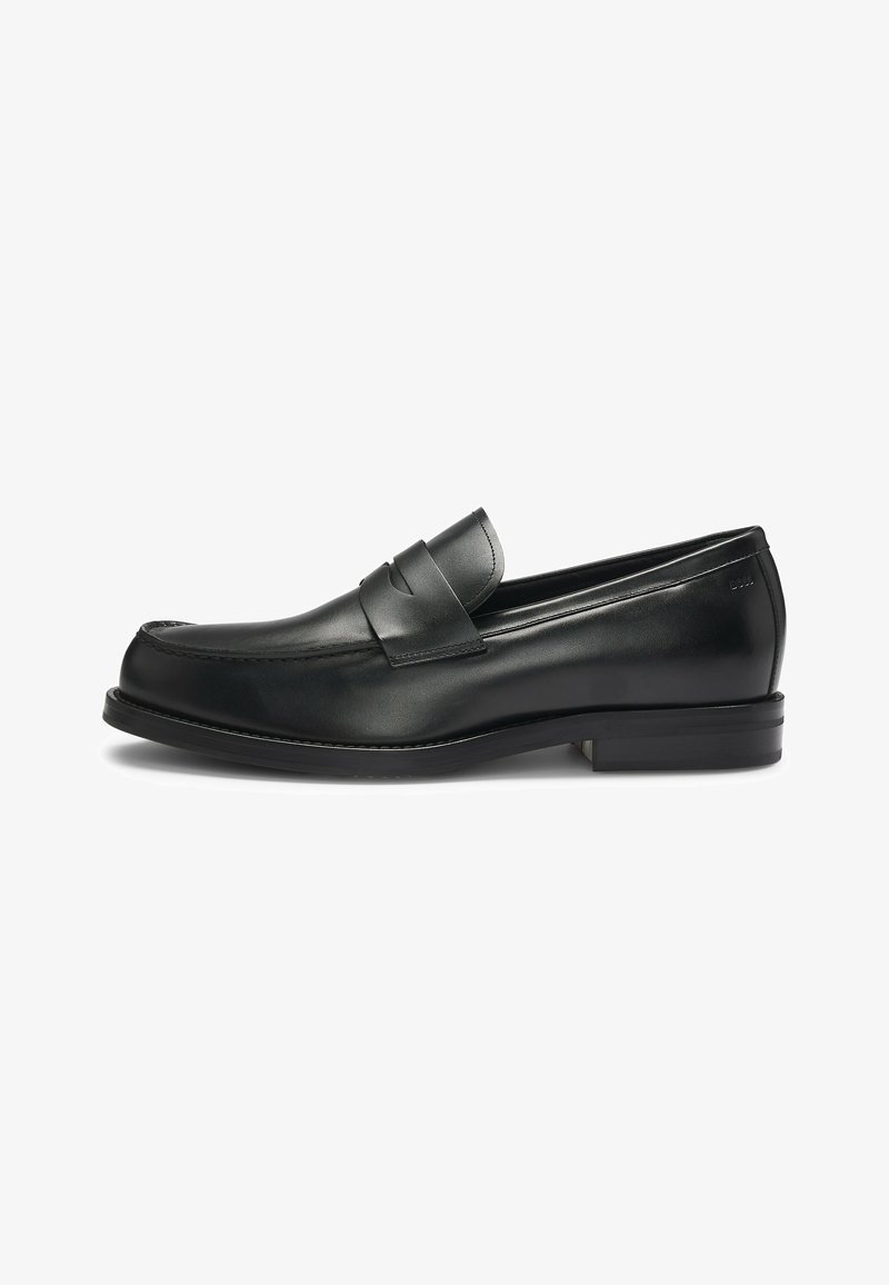 Black leather loafers with a rounded toe and stitched detailing, featuring a decorative strap across the upper and a low heel.