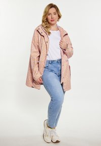 Peonā krāsa ar leopardu rakstu apģērbs ar kapuci, snap pogām un brīvu piegriezumu, apvienots ar gaiši ziliem džinsiem un baltām sporta apaviem.