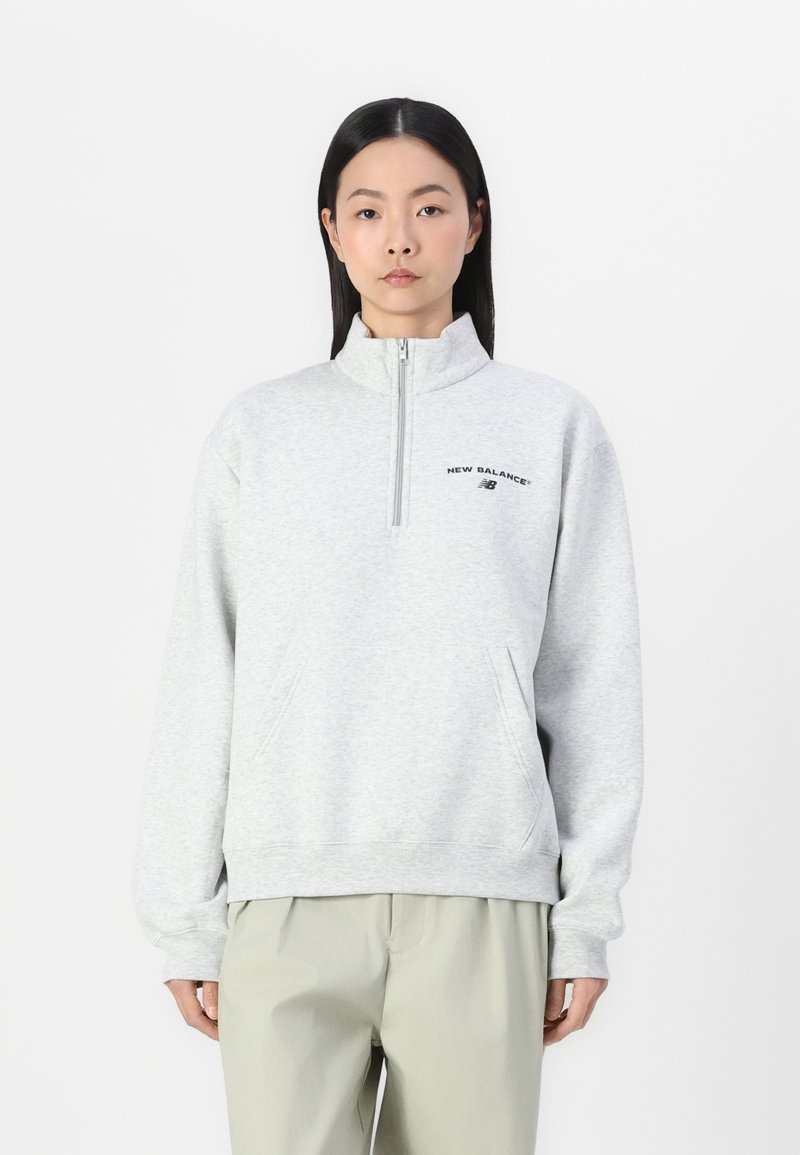 Sudadera de color gris claro con cremallera de cuarto hecha de tela de sudadera, con un bolsillo frontal, presenta un logotipo negro en el pecho y puños elásticos.