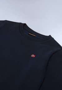 Felpa blu navy realizzata in cotone, con scollatura tonda e polsini a coste. Presenta un piccolo distintivo con bandiera norvegese rossa e bianca.