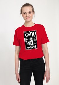 Rød bomulds T-shirt med et sort grafisk print med ordene "ALIEN INDBRUD" og et tegneserieagtigt alien-design. Korte ærmer, afslappet pasform.