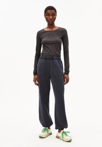 Gestreiftes Langarmshirt in Dunkelgrau und Schwarz, kombiniert mit navyblauen, lässigen Sweatpants. Strukturiertes Gewebe, elastischer Bund und gepolsterte Bündchen.