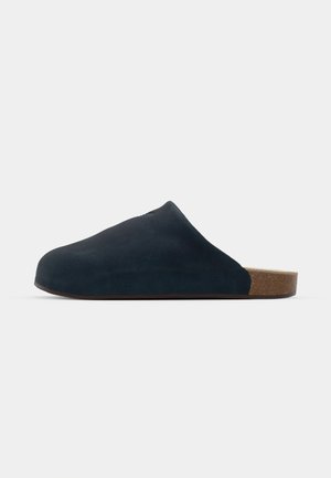 Marineblå ruskinds slip-on mule med rund tå, korksål og glat tekstur. Har et minimalistisk design uden pynt.