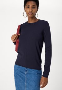 Ναυτικό μπλουζάκι με μακρύ μανίκι σε απαλό, ελαφρύ ύφασμα, συνδυασμένο με τζιν φούστα. Διαθέτει στρογγυλή λαιμόκοψη και άνετη εφαρμογή.