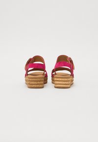 Rosa semskede sandaler med avrundet form, med en korkkilehæl og en dekorativ spenne på stroppen. Enkelt design, teksturerte materialer.