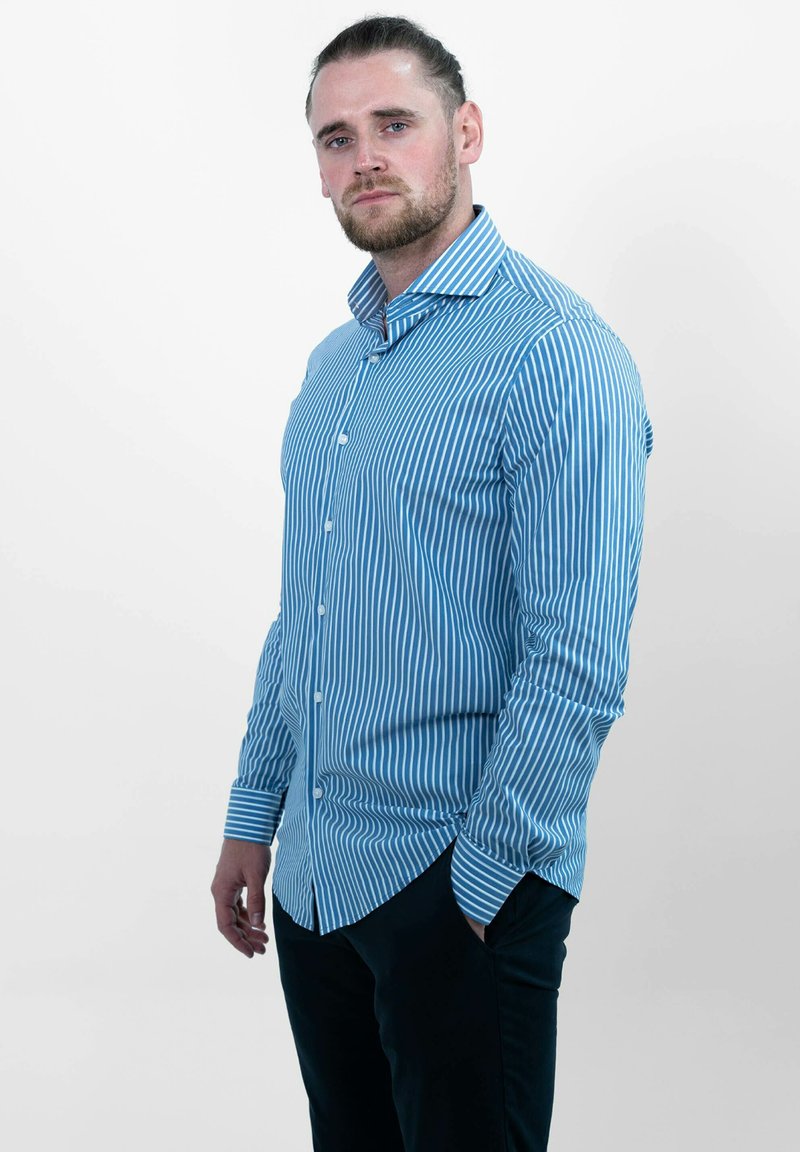 Blauwe gestreepte overhemd met lange mouwen, voorzien van verticale witte strepen, een puntige kraag en een gebogen zoom, gecombineerd met donkere broek.