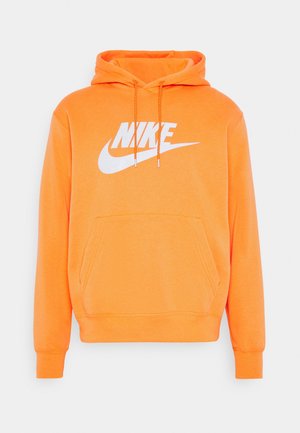 Jasnopomarańczowa bluza z kapturem, z przodu kieszeń kangurka oraz duże białe logo Nike i znak Swoosh na piersi.