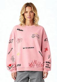 Felpa rosa con grafiche ricamate che includono fiori, serpenti e testo. Caratterizzata da una vestibilità comoda e un colletto a costine.