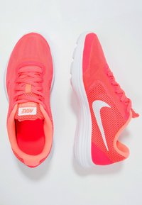 Pair of bright coral pink Nike running shoes with white swoosh logos and white soles on a light background.