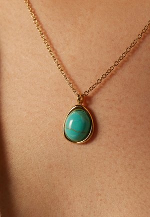 Turkooise hangende ketting aan een gouden ketting. Druppelvormige steen met aderen, gezet in een gladde gouden zetting. Ketting heeft een gelinkte ontwerp.