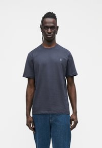 Granatowy bawełniany t-shirt z krótkimi rękawami, okrągłym dekoltem oraz małym białym logo "II" na lewej piersi. Luźny krój, bez widocznych wzorów czy akcentów.