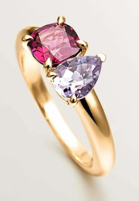 Anillo de oro con dos piedras preciosas: un corte cojín rosa y un corte pera lavanda, ambos engastados en un diseño de garra, resaltando su brillantez.