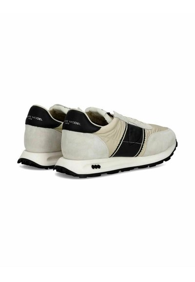 Sneakers med en beige og sort farvepalette, lavet af ruskind og syntetiske materialer, med teksturerede detaljer og en holdbar gummisål.