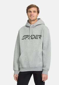 Felpa grigia con cappuccio e tasca a marsupio frontale, caratterizzata dalla scritta "SPYDER" in bold nero attraverso il petto. Materiale in cotone morbido.