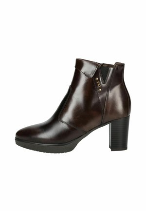 Bottine en cuir marron avec un bout pointu, des panneaux latéraux élastiques et un talon bloc texturé. Présente un petit accent métallique près de la cheville.