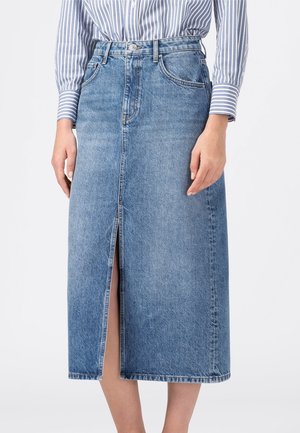 Mittellanger blauer Jeansrock mit vorderem Schlitz, kombiniert mit einem blau-weiß gestreiften Hemd, das vorne eingesteckt ist.