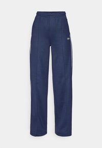Navy blue athletic pants made of soft fabric, featuring a relaxed fit, elastic waistband, and white side stripes. Green logo accent on leg.