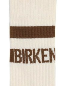 Calcetín color crema con rayas horizontales marrones y el texto "BIRKEN" en una textura de punto. Presenta detalles acanalados en la parte superior.