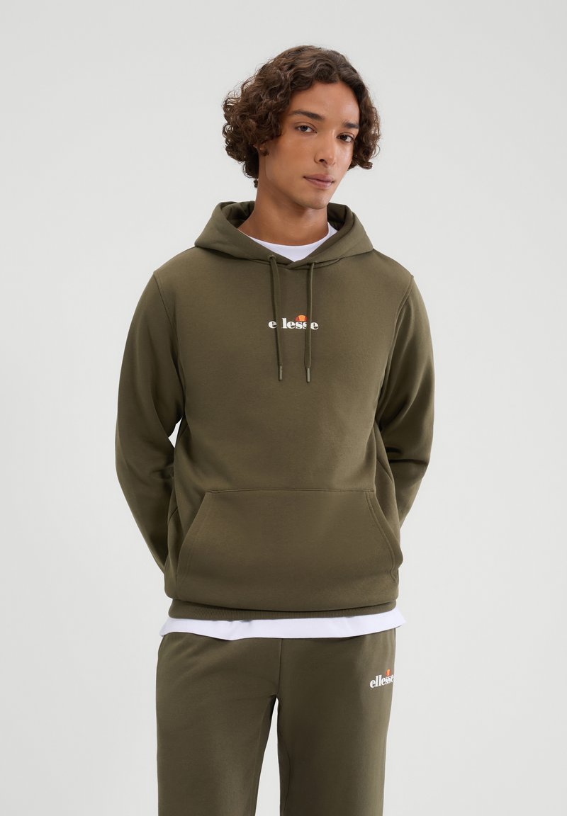Oliwkowa bluza z kapturem z kieszenią kangurzą, z białym logo na piersi, kapturem na sznurki i ściągaczami na rękawach. Połączona z pasującymi spodniami dresowymi.