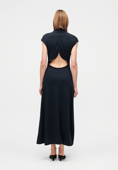 Fekete, ujjatlan maxiruha magas nyakkal és kulcslyuk kivágással a hátulján. Puha textúrájú, áramló kialakítású, bokáig érő szegéllyel.