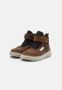 Braune Wildleder-Hochtop-Sneaker mit schwarzen Textilakzenten, ausgestattet mit Klettverschlüssen und einem weißen Logo-Patch, auf einer leicht gefederten Gummisohle.