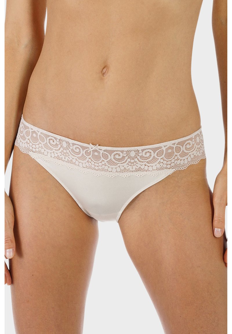 Beige underkläder med ett spetsmidja med intrikata mönster och en liten rosett i mitten. Mjuk, slät tygtextur.