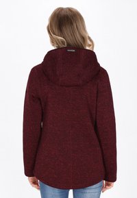 Maroon, textured hoodie with a fitted design and large hood. Features a curved hem and subtle stitching details. Suitable for casual wear.