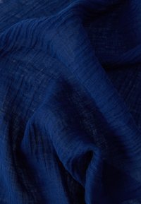 Σκούρο μπλε υφαντό ύφασμα με εμφανή υφή ύφανσης και απαλές πτυχώσεις που δημιουργούν σκιές και φωτισμούς.