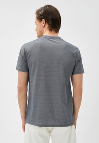Camiseta gris de manga corta hecha de un tejido suave y texturizado, con un cuello redondo y un corte clásico, sin patrones ni acentos visibles.