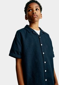 Camicia a maniche corte, blu scuro, con un motivo testurizzato, apertura a bottoni e polsini ripiegati, realizzata in tessuto leggero.