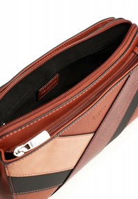 Braune Lederhandtasche mit geometrischem Design, ausgestattet mit schwarzen und hellbraunen Akzenten, Reißverschluss und strukturiertem Finish. Das Innere ist schwarz.