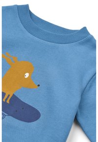 Sweatshirt bleu avec un graphisme de chien marron sur un skate. La texture est douce avec un col côtelé et des couleurs vives.