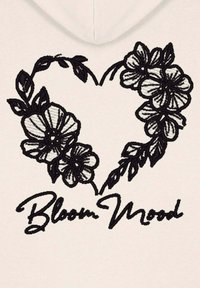 Sudadera blanca con un diseño floral negro bordado en forma de corazón y el texto "Bloom Mood" en una fuente elegante debajo.