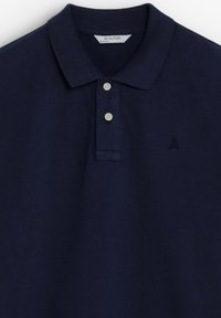 Polo bleu marine en tissu texturé, présentant un col classique, une patte de boutonnage à trois boutons et un logo brodé sur la poitrine gauche.