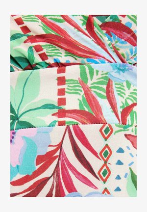 Lyst tropisk stof med røde, grønne og blå blade, geometriske mønstre og overlappende folder, der skaber tekstur og dybde.