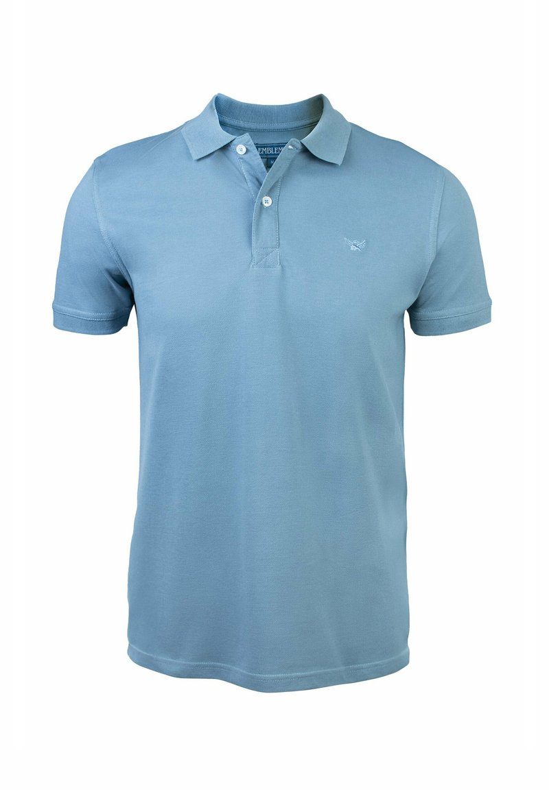 Polo de color azul claro, hecho de algodón, con cuello, tapeta de tres botones y un pequeño logo en el pecho. Mangas cortas.