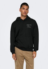Black hoodie made of cotton-blend fabric, featuring a front kangaroo pocket and white text “GANGSTERS BUY FLOWERS” on the chest.