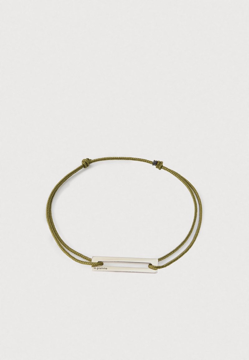 Podesivi ogrlica od zeleno-maslinaste pletene žice s pravokutnom srebrnom šipkom na kojoj je ugravirano "le gramme" na jednostavnoj pozadini.