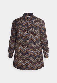 Button-up skjorte lavet af let materiale, med et zigzag-mønster i marineblå, orange og creme. Lange ærmer med manchettter.