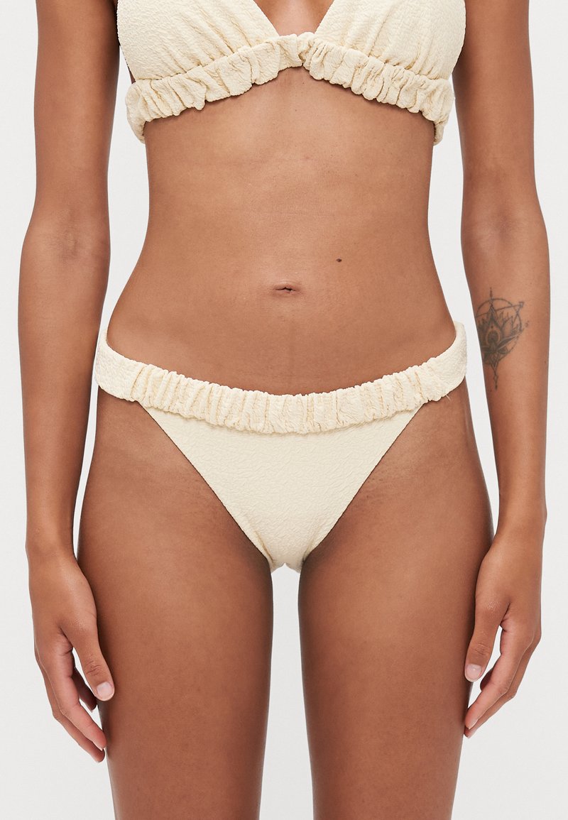 Cremfarbener Bikini aus strukturiertem Stoff, mit gerafften Rändern an Ober- und Unterteil und einem minimalistischen Design mit einem dreieckigen Bralette.