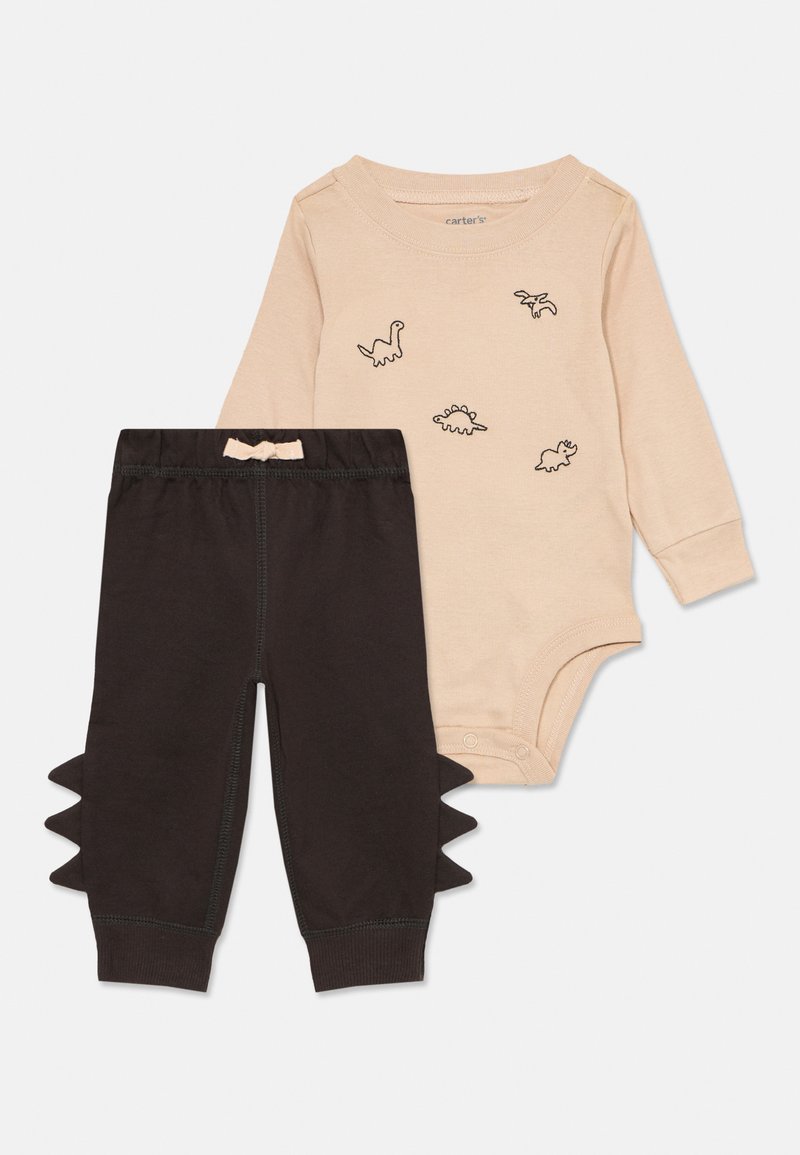 Beiger langärmliger Baby-Body mit schwarzen Dinosaurier-Silhouetten, kombiniert mit schwarzen Hosen, die an den Seiten Stoffspitzen haben.